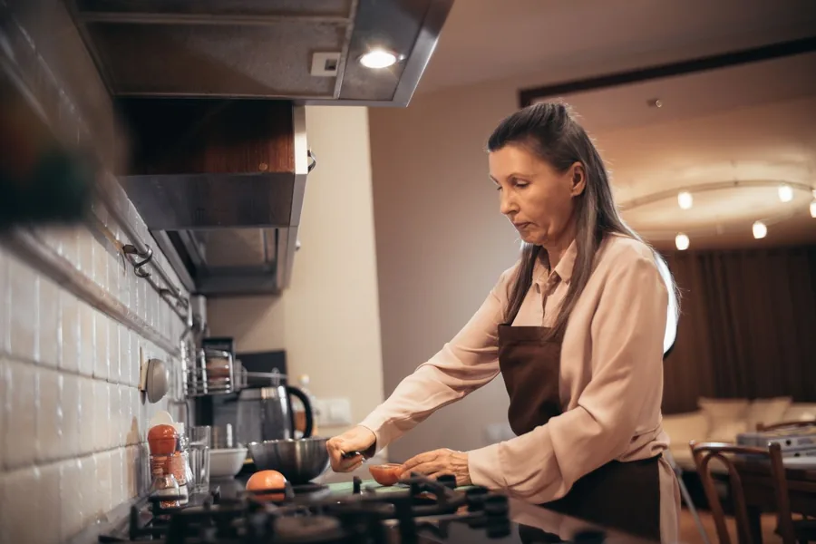 A caregiver preparing a home-cooked meal at the stove in a client's kitchen